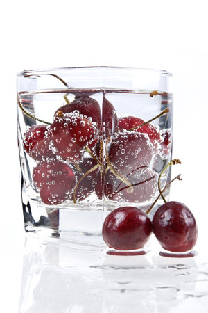 Glass with mineral water and sweet cherry makes thirsty