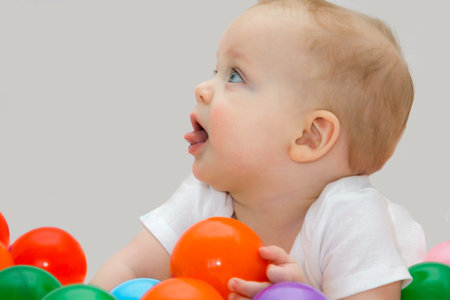 Looking up blond 8 month baby boy playing with color ballsの写真素材