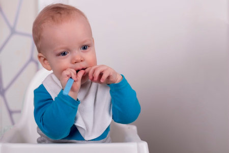 Calm beauty little kid in baby chair in the kitchen