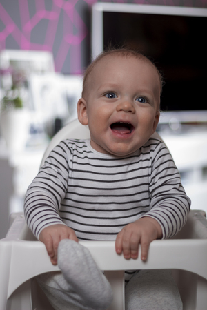 Funny smiling kid in baby chairの写真素材