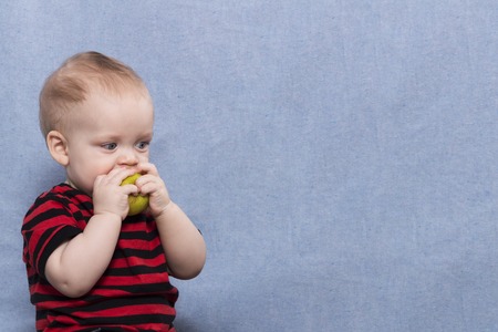 Pretty little kid eating big green appleの写真素材