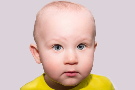 Serious blue-eyed toddler looking at cameraの写真素材
