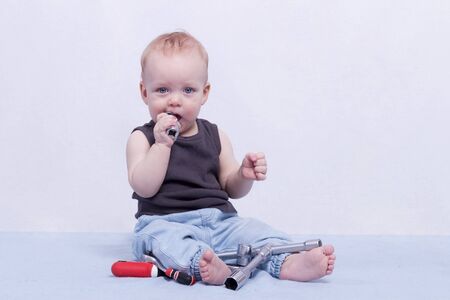Funny little boy with building tools in his mouthの写真素材