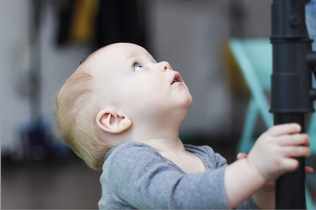 Cute blue-eyed 10-month-old baby boy looking upの写真素材
