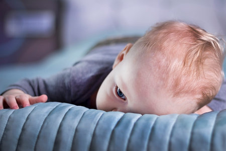 Bored baby boy lying on the bed. Calm infant kid on the bed. Tired toddlerの写真素材