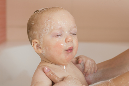 Mother washing a baby boy. Funny infant boy taking a bath. Toddler boy after drowning out of water.の写真素材