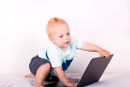Cute toddler closes down a laptop. Concept of new generation.の写真素材