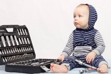 Funny little boy with set of tools against grey wallの写真素材