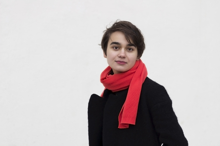 Dramatic Portrait of young melancholy woman in a red scarf against cocrete wall. Concept of loneliness. Copy space. Street shotの写真素材