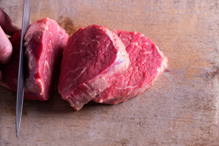 Butcher cutting beef meat on kitchen. Top view.の写真素材