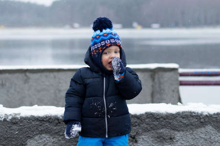 Funny toddler eating snow. Surprised with a new taste. Winter shotの写真素材