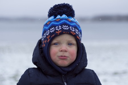 Toddler with snivel and red cheeks. Outdoor winter shotの写真素材