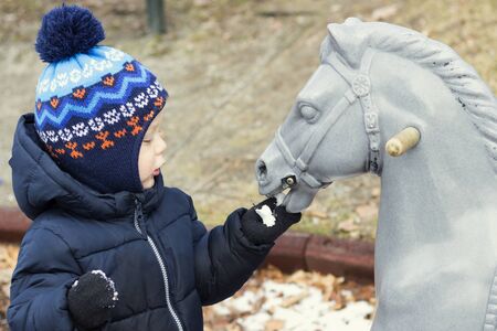 Two year toddler playing with a toy horse. Kid feeding wooden horseの写真素材