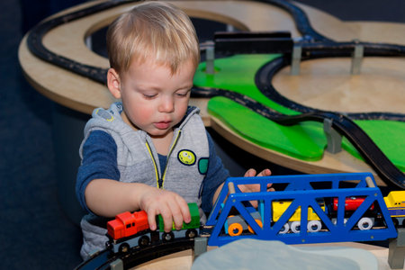 Cute toddler playing with a toy train in children center