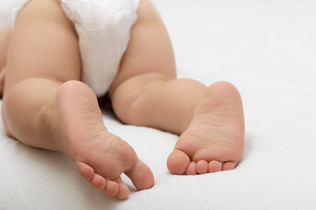 Legs of a baby with diaper on a white blanketの写真素材