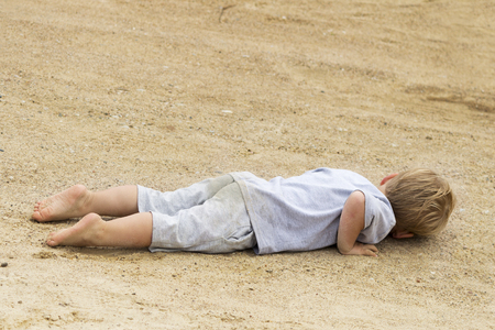 young toddler child boy laying in the sand. copy spaceの写真素材