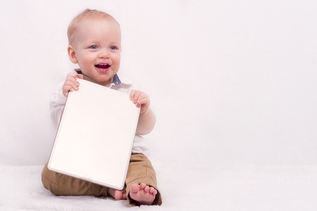 Cute baby boy holding a banner against white background. Copy spaceの写真素材