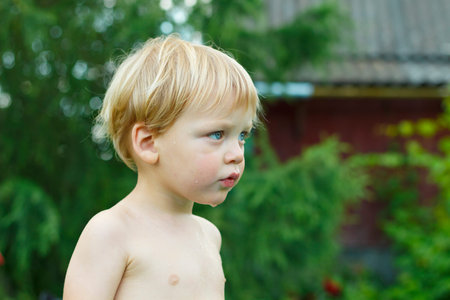 Cute baby boy with a wet face in the garden. Hot summer day. in a country house. copy spaceの写真素材