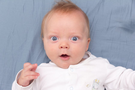 Portrait of cute smiling baby lying on the bed at home, top view