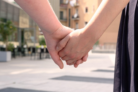 Closeup of the hands of a boy and girl walking on the street holding hands. Boy and girl walking on...