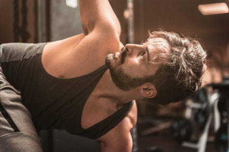 A bearded sporty man in the gym is doing Yoga and Martial Arts exercises. Revolved Triangle Pose....
