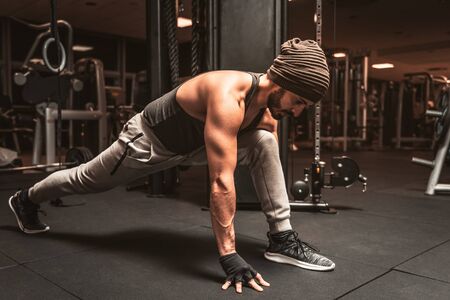 A sporty man in the gym is doing Yoga exercises. Virabhadrasana: the position of the Warrior. Yoga mental benefits.の写真素材