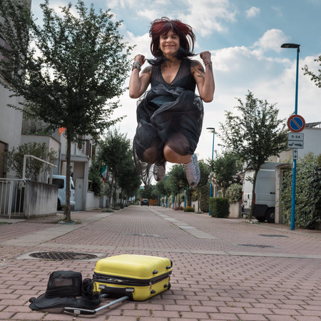 Traveler woman with suitcase jumping in the city outdoors. Tourist travel lifestyle.