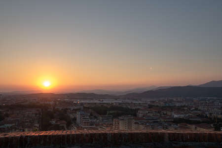 Aerial panoramic sunset view of residential district with buildings of Brescia city and Alps mountain range, blue cloudy sky background, Lombardy, Northern Italy. Brescia Castle.の写真素材