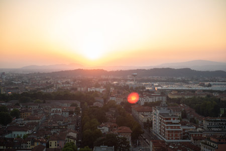 Aerial panoramic sunset view of residential district with buildings of Brescia city and Alps mountain range, blue cloudy sky background, Lombardy, Northern Italy. Brescia Castle.の写真素材