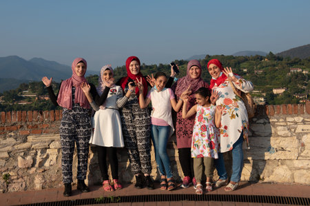 Egyptian women pose in front of camera on the roof terrace with aerial view of the old Italian city of Brescia.のeditorial素材