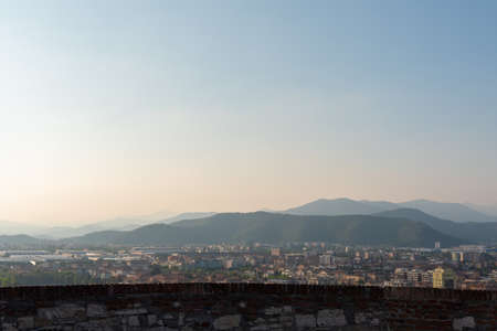 Aerial panoramic sunset view of residential district with buildings of Brescia city and Alps mountain range, blue cloudy sky background, Lombardy, Northern Italy. Brescia Castle.の写真素材