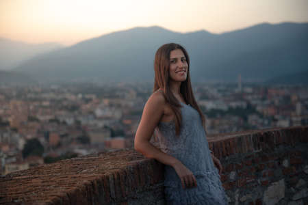 Woman on the roof terrace with aerial view of the old Italian city Brescia at sunset.の写真素材