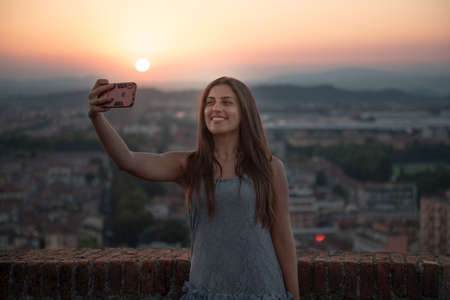 Woman on the roof terrace with aerial view of the old Italian city Brescia at sunset.の写真素材