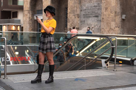 Young girl at the entrance to the subway. Miniskirt. Boots. Smartphone.の写真素材