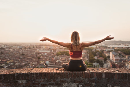 Woman practicing yoga or pilates at sunset or sunrise in beautiful city location.