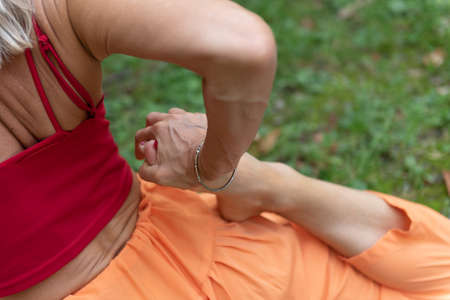 Woman practicing yoga in nature. Part of the body. Arm and leg in the foreground. Performs a pigeon pose and further stretches your quads.の写真素材
