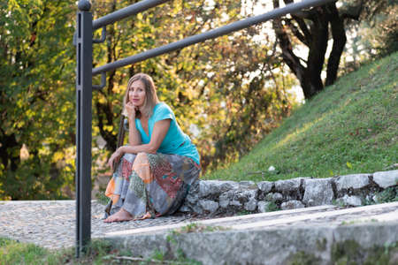Adult woman with blond hair sitting in natureの写真素材