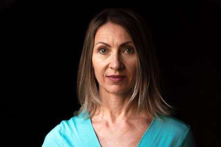 Portrait of adult woman with blond hair on dark backgroundの写真素材
