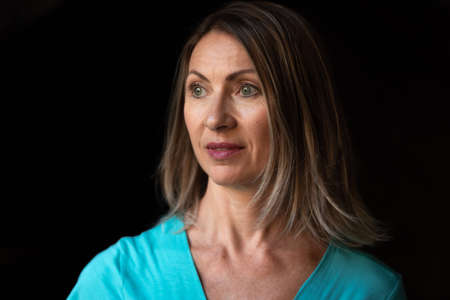 Portrait of adult woman with blond hair on dark backgroundの写真素材