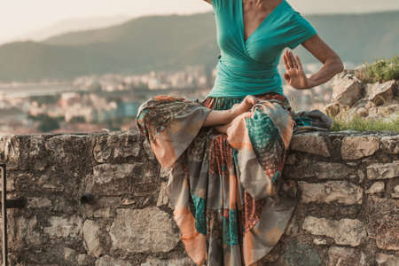 Adult woman does sports exercise. Yoga teacher doing an asana on the old city wall.の写真素材