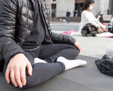 Yoga teachers protesting against the blockade and restrictions of Covid-19 in a square in Brescia, Italy. Shot of the hands resting on the knees of the crossed legs. People are meditating.の写真素材