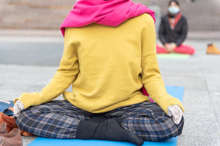 Yoga teachers protesting against the blockade and restrictions of Covid-19 in a square in Brescia, Italy. Shot of the hands resting on the knees of the crossed legs. People are meditating.の写真素材