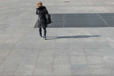 Blond woman walking and carrying briefcaseの写真素材
