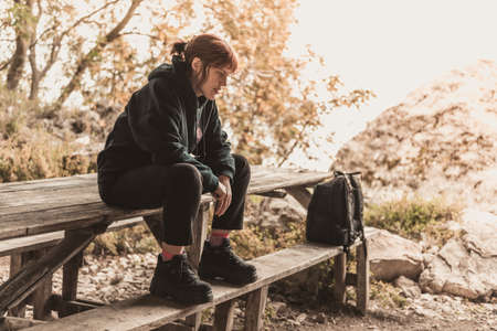 Young woman sitting at the wooden table in the autumn park.の写真素材