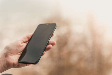 Closeup image of female hands using smartphone in mountain day, search or social network concept, hipster woman typing a sms message to her friendsの写真素材