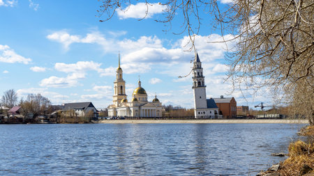 Leaning Tower of Nevyansk and Old Believers' church (domed) in spring day on the shore of the pond...