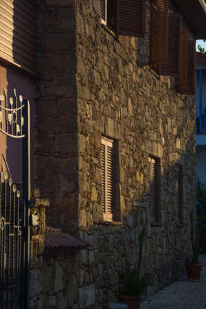 A vertical shot of a stone wall with window shutters in the backgroundの写真素材