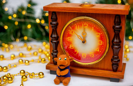 A toy brown bull near the old clock showing midnight. A branch of a Christmas tree with golden garlands in the background. The bull as a symbol of the new year 2021. New Year, Christmas conceptの写真素材