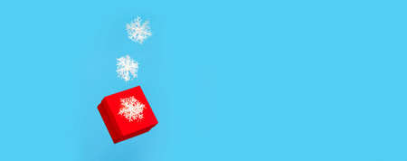 The red gift box with white snowflakes levitate on a blue background. A place for text. Banner. New Year, Christmas - the concept of the holidayの写真素材