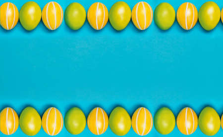 Frame for text from easter eggs in yellow and green on a blue background. Banner. Greeting card. Place for text. Happy Easter. A row of multi-colored eggsの写真素材